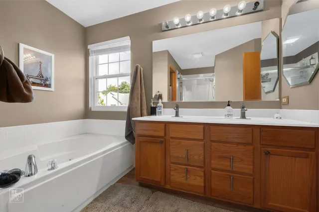 a bathroom with a tub a sink and mirror