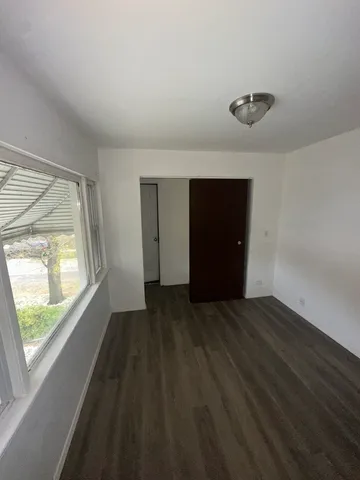 a view of an empty room with a window and a kitchen