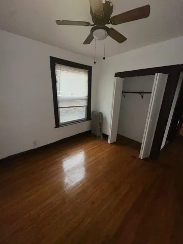 an empty room with wooden floor closet and windows