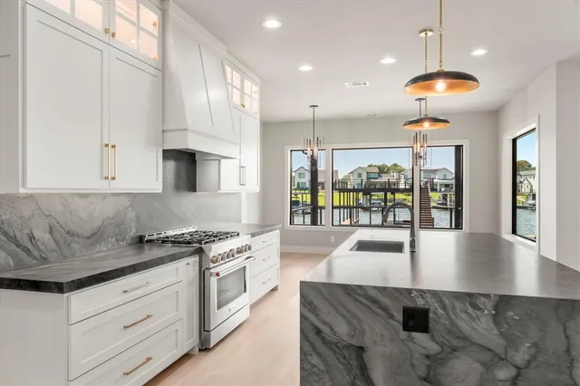 a kitchen with stainless steel appliances granite countertop a stove a sink and a granite counter tops with white cabinets