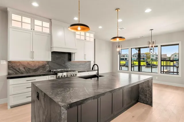 a kitchen with stainless steel appliances granite countertop a sink a oven and a large window with wooden floors