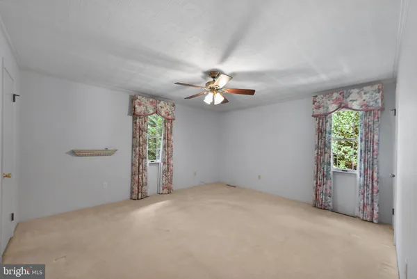 an empty room with windows and chandelier fan