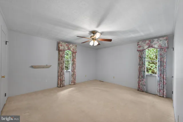 an empty room with windows and chandelier fan