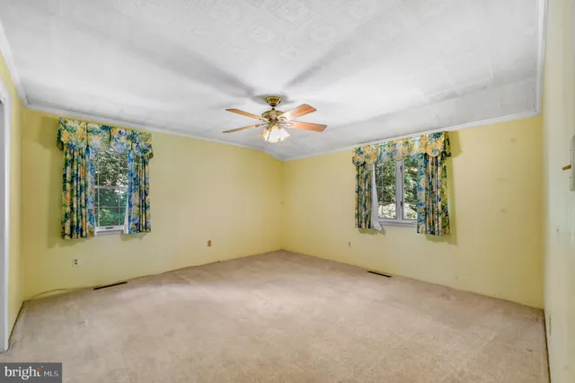 an empty room with windows and chandelier fan