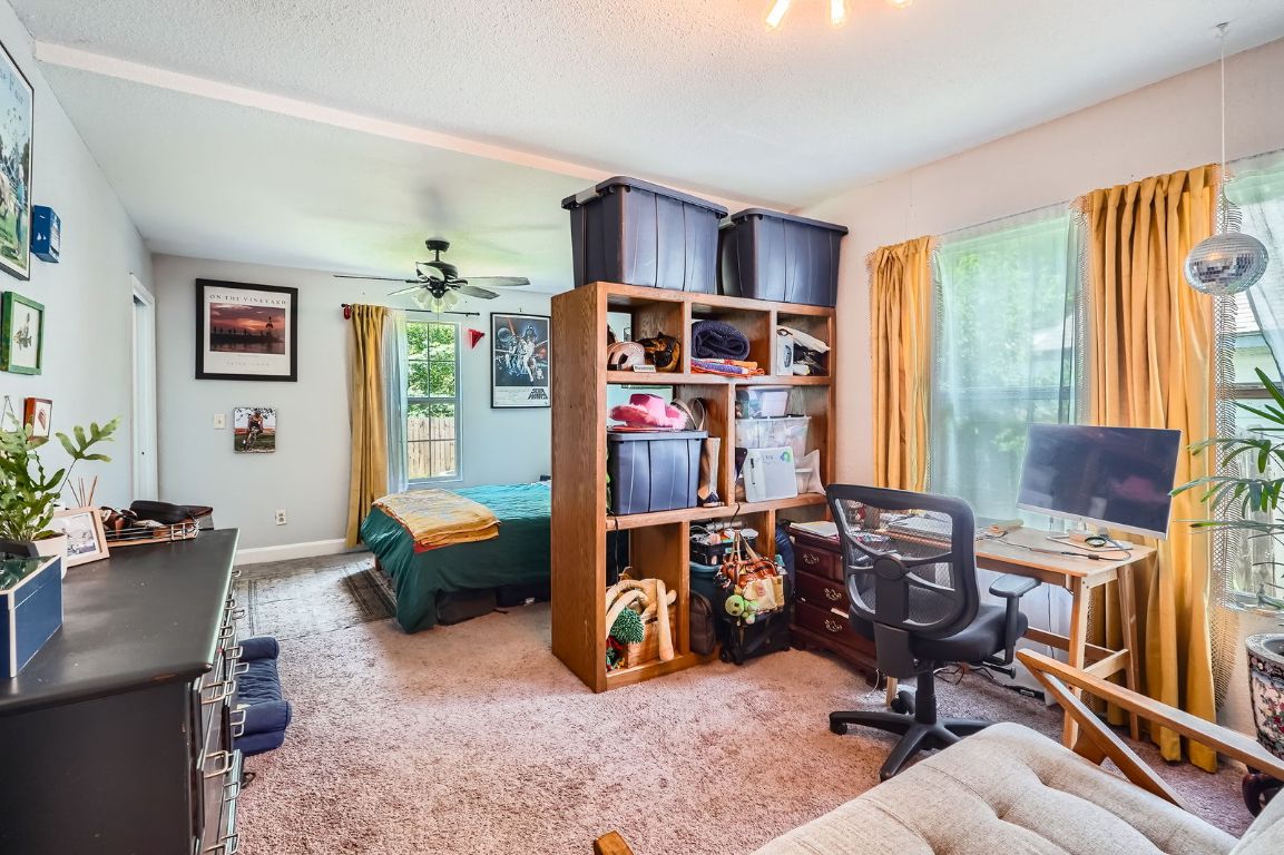 5605 Tura Lane Austin, TX 78721 - Photo 3 of 11 Bedroom with light colored carpet, an office area, a ceiling fan, and a textured ceiling