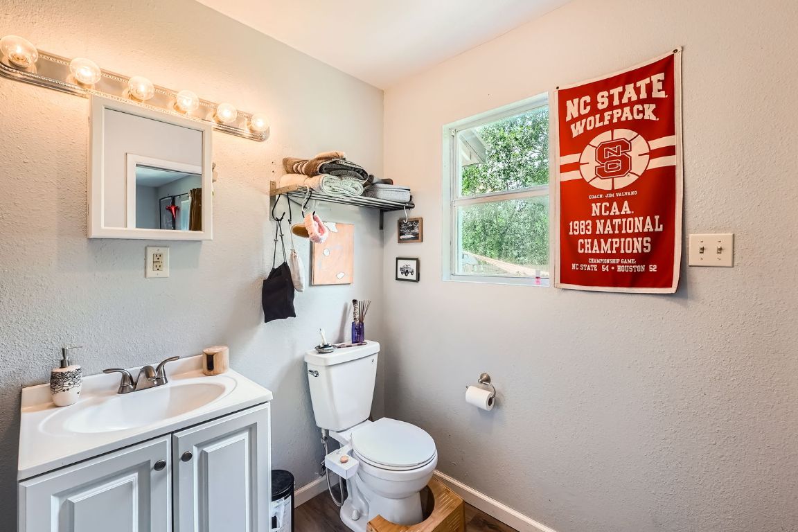 5605 Tura Lane Austin, TX 78721 - Photo 7 of 11 Half bathroom with a textured wall, vanity, and wood finished floors