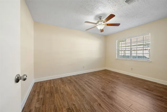 an empty room with wooden floor chandelier and windows