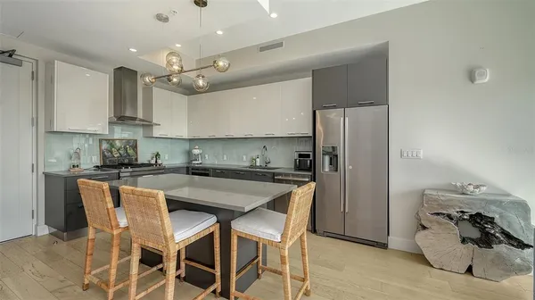 a kitchen with stainless steel appliances granite countertop a sink a stove a refrigerator and island with wooden floor