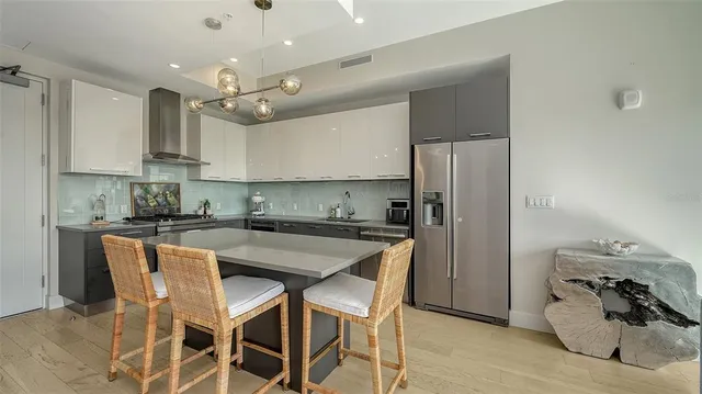 a kitchen with stainless steel appliances granite countertop a sink a stove a refrigerator and island with wooden floor