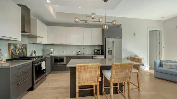 a kitchen with stainless steel appliances granite countertop a stove top oven a refrigerator a sink and chairs