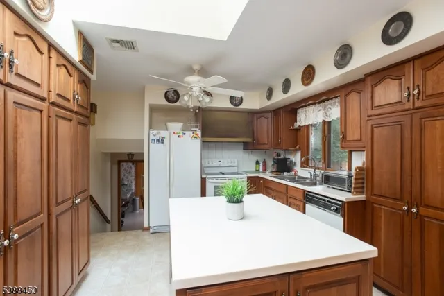 a kitchen with stainless steel appliances granite countertop a refrigerator a stove and a sink with wooden floor