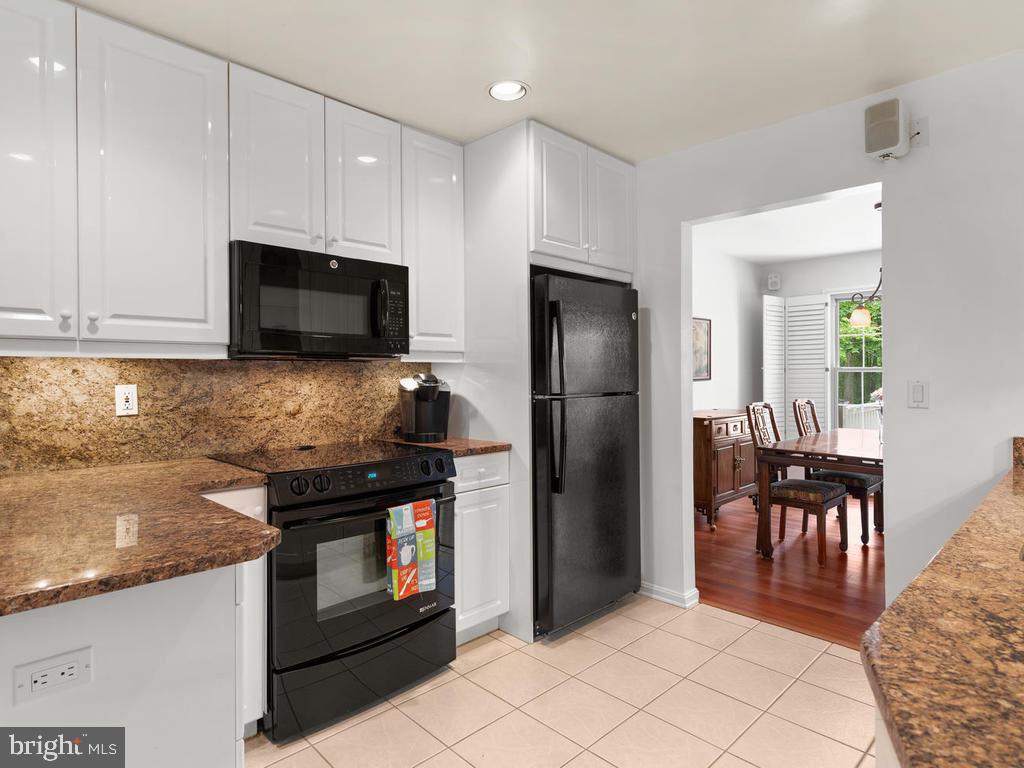600 Bryants Nursery Road Silver Spring, MD 20905 - Photo 17 of 60 a kitchen with granite countertop a refrigerator a stove a sink a dining table and chairs