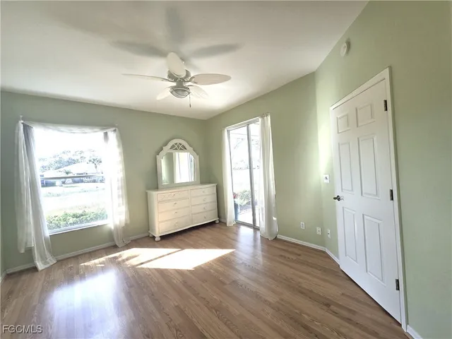 an empty room with wooden floor chandelier and windows