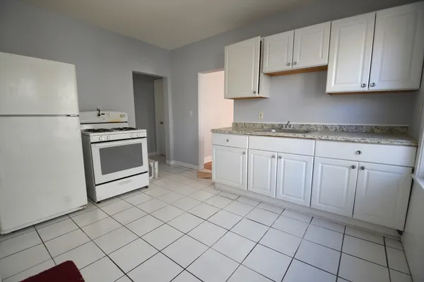 a kitchen with granite countertop white cabinets and white appliances