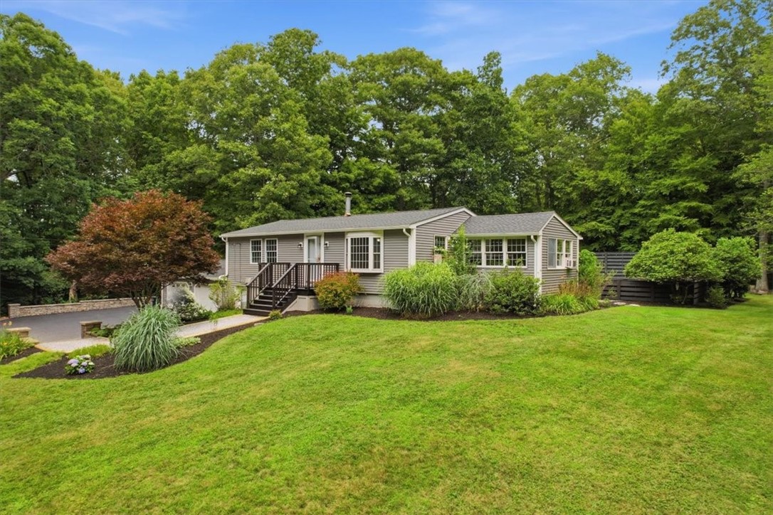 214 Anan Wade Road Glocester, RI 02857 - Photo 3 of 50 A gravel walkway leads through the landscaped beds to the front steps, while stone retaining walls add character and structure around the driveway and garden areas.