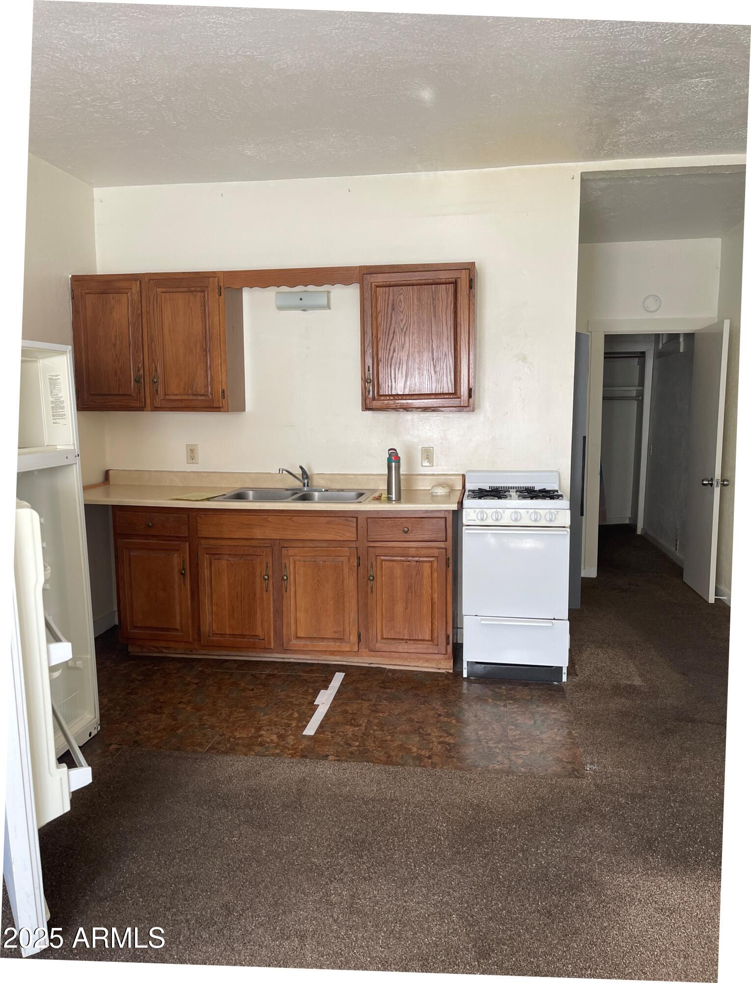 102 Opera Drive, Unit B Bisbee, AZ 85603 - Photo 2 of 8 Kitchen with hallway to bathroom and bed