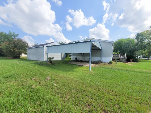 a backyard of a house with plants and large tree