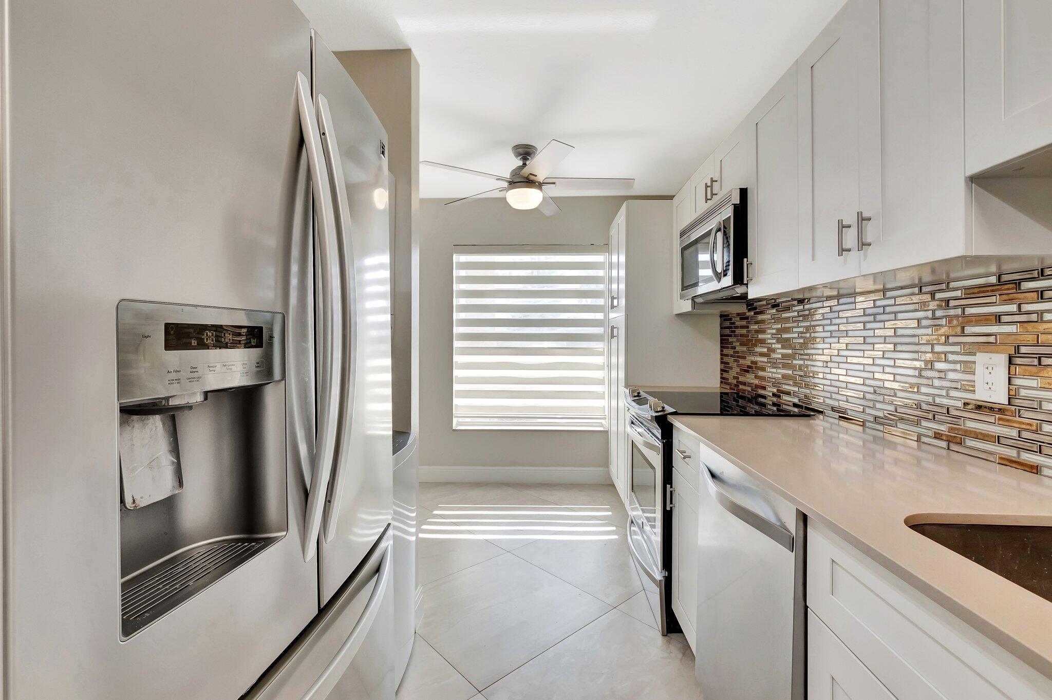 1131 Violet Terrace, Unit 104 Delray Beach, FL 33445 - Photo 13 of 36 a kitchen with stainless steel appliances granite countertop a sink and a refrigerator