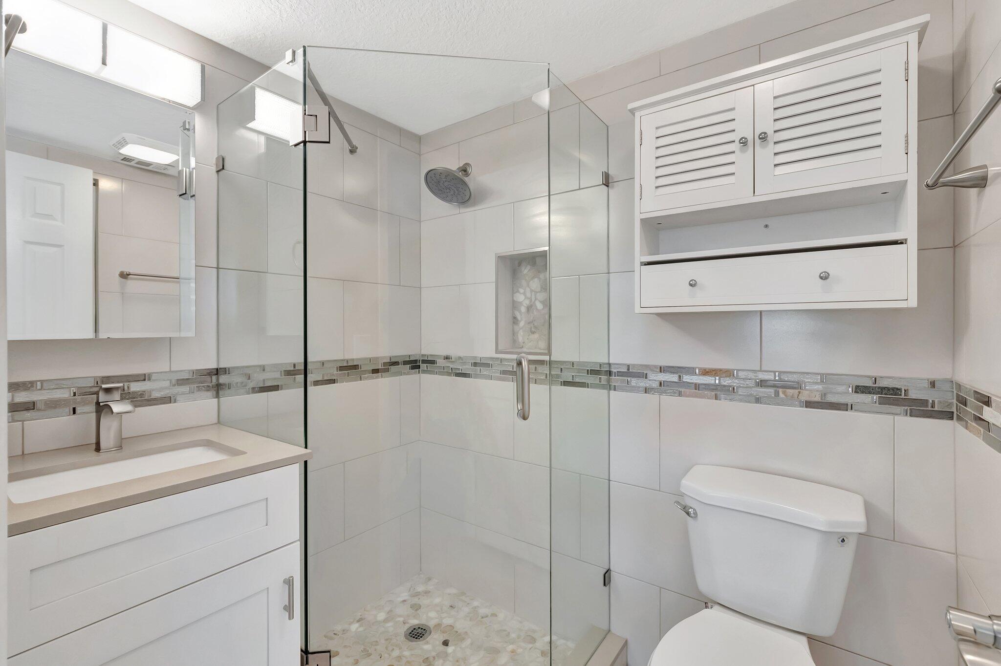 1131 Violet Terrace, Unit 104 Delray Beach, FL 33445 - Photo 18 of 36 a bathroom with a shower a sink and a mirror