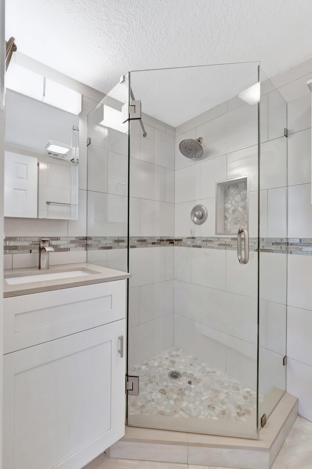 1131 Violet Terrace, Unit 104 Delray Beach, FL 33445 - Photo 19 of 36 a bathroom with a shower sink and mirror