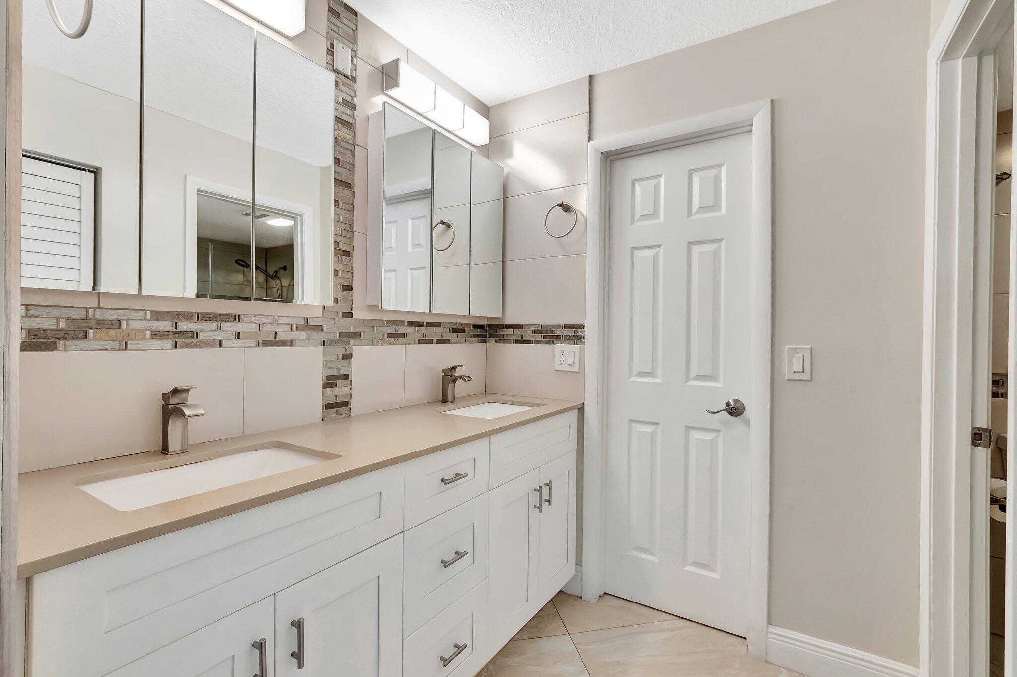 1131 Violet Terrace, Unit 104 Delray Beach, FL 33445 - Photo 22 of 36 a bathroom with double sink and a mirror