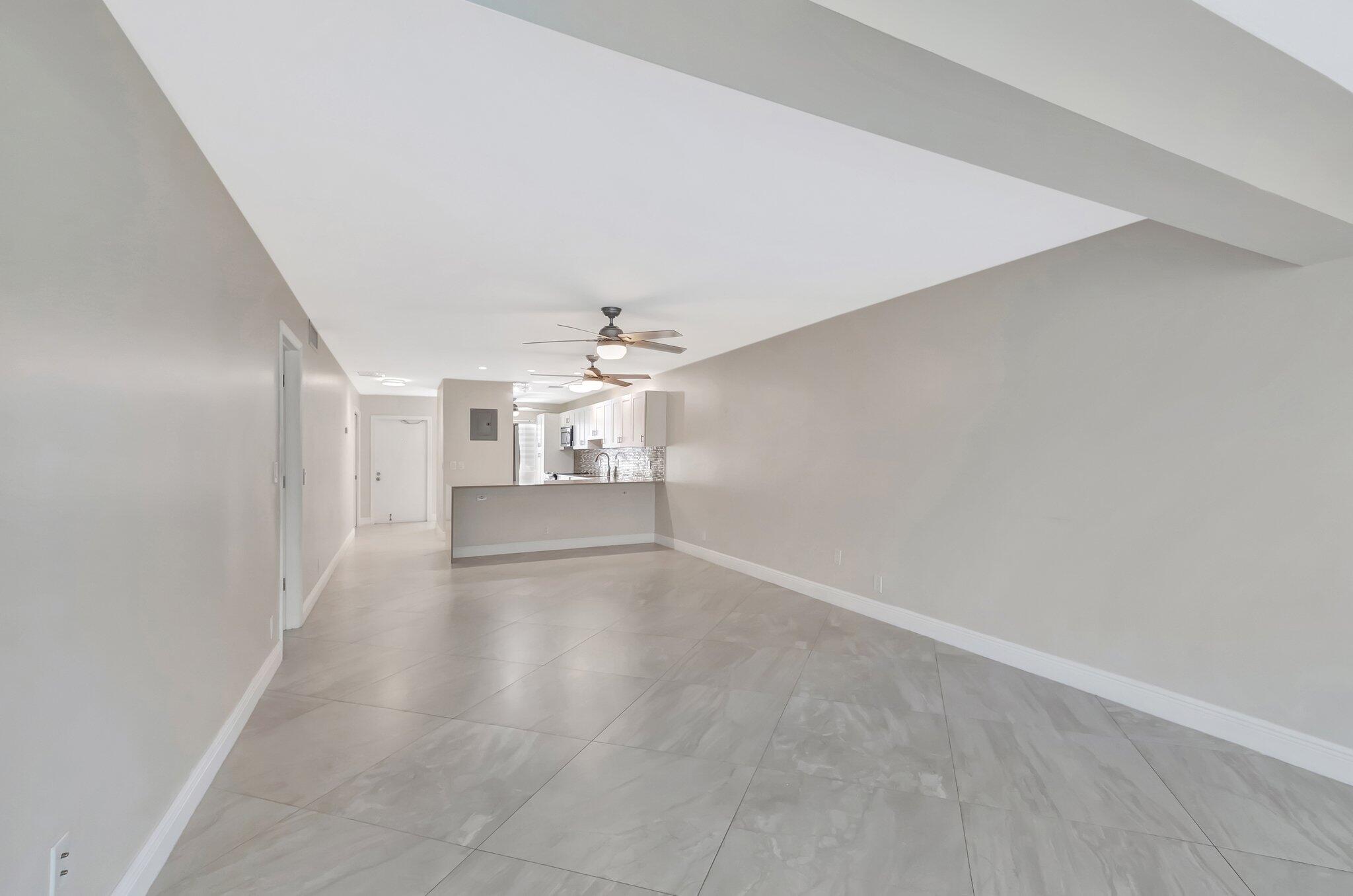 1131 Violet Terrace, Unit 104 Delray Beach, FL 33445 - Photo 6 of 36 an empty room with chandelier fan and windows