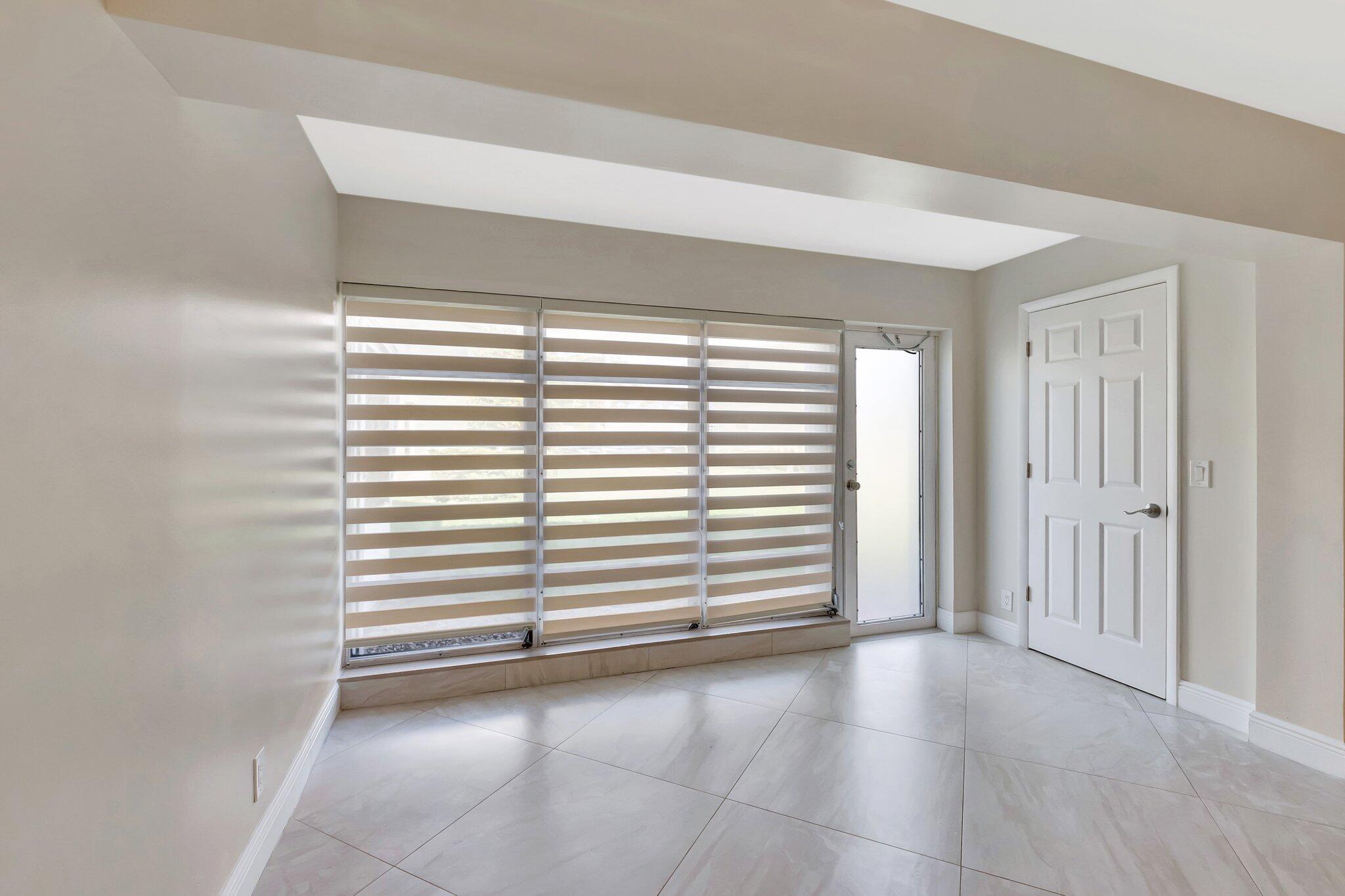 1131 Violet Terrace, Unit 104 Delray Beach, FL 33445 - Photo 7 of 36 an empty room with windows and entrance