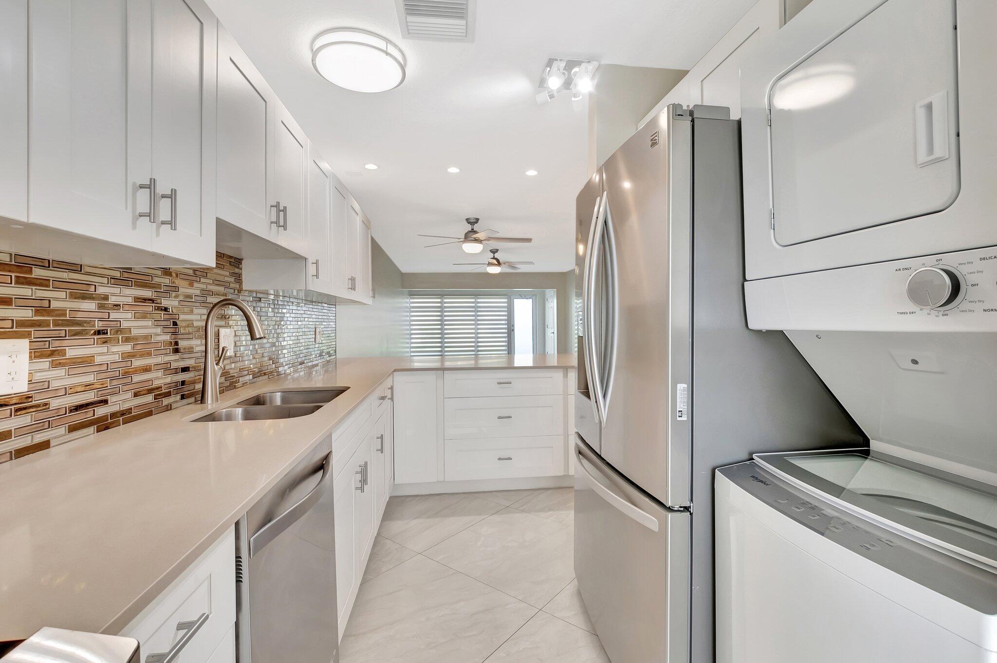 1131 Violet Terrace, Unit 104 Delray Beach, FL 33445 - Photo 10 of 36 a kitchen with a sink a stove and refrigerator