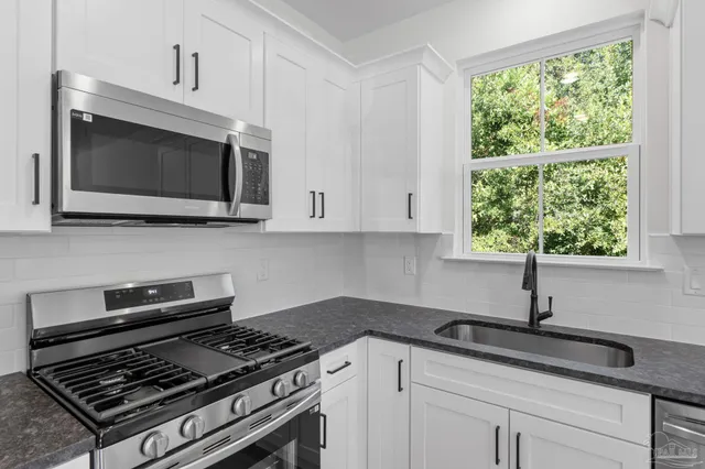 a kitchen with kitchen island white cabinets appliances and window
