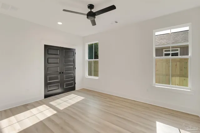 an empty room with windows closet and chandelier fan