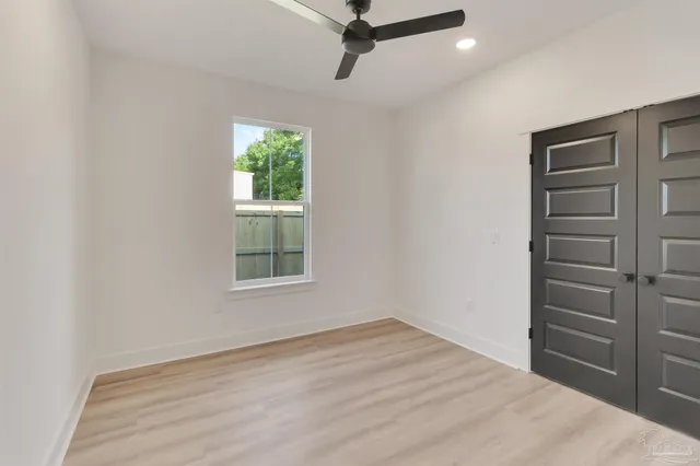 a view of empty room with wooden floor and fan