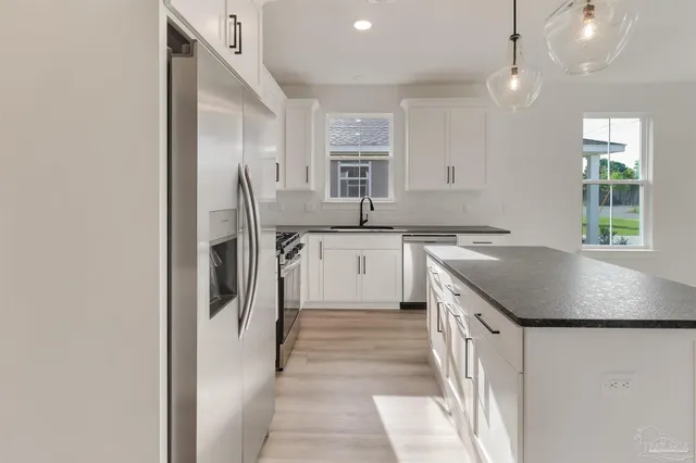 a kitchen with stainless steel appliances granite countertop a sink stove and refrigerator
