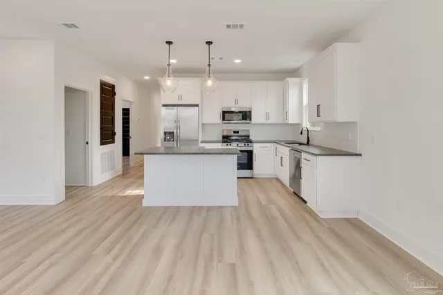 a large kitchen with stainless steel appliances lots of counter space and wooden floors