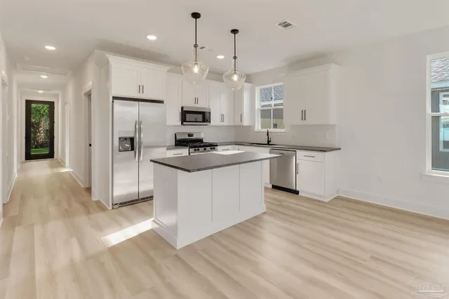 a kitchen with kitchen island a sink stainless steel appliances and white cabinets