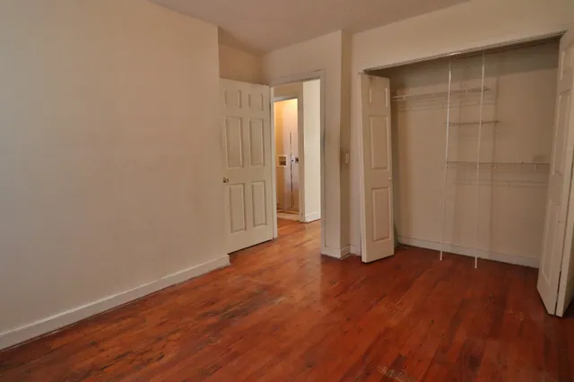 an empty room with wooden floor and closet area