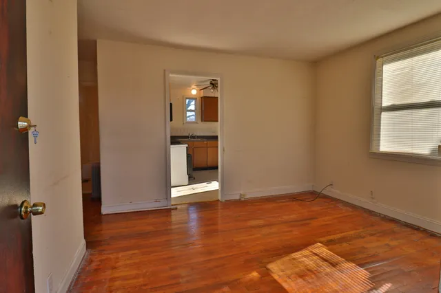 an empty room with wooden floor mirror and windows