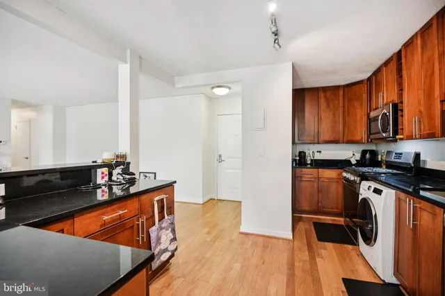 a kitchen with stainless steel appliances a sink dishwasher stove refrigerator with wooden floor
