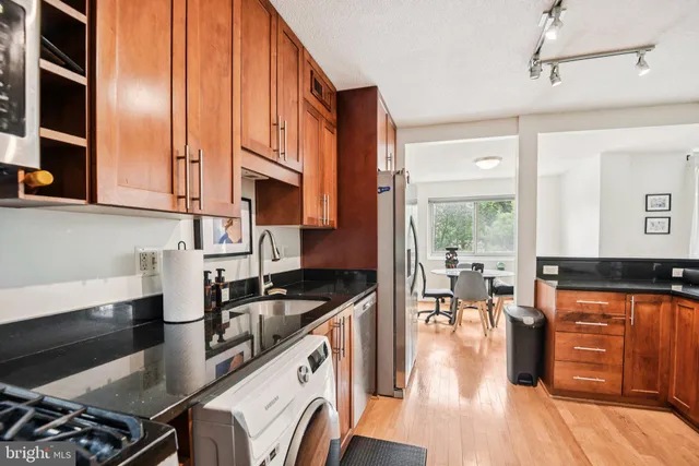 a kitchen with granite countertop a stove a sink and a wooden cabinets