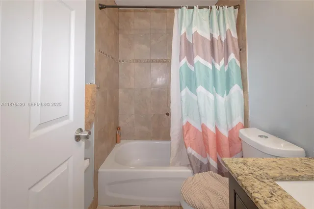 a bathroom with a granite countertop bathtub sink vanity and toilet