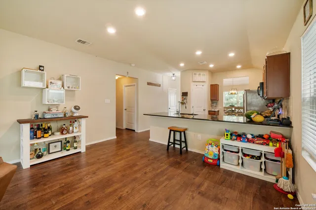 a open kitchen with stainless steel appliances granite countertop a refrigerator a stove and a dining table with wooden floor