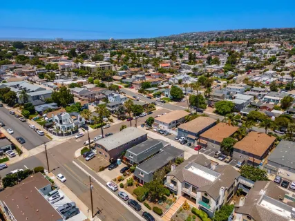 an aerial view of a city with lots of residential buildings and ocean view in back