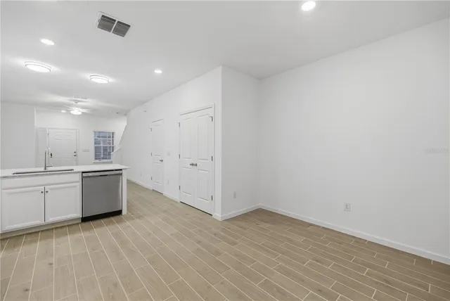 a large kitchen with a wooden floor and white stainless steel appliances