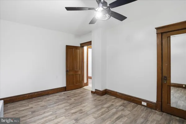 an empty room with wooden floor closet and fan