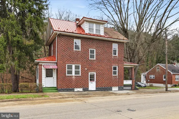 a view of a house with a yard and large tree