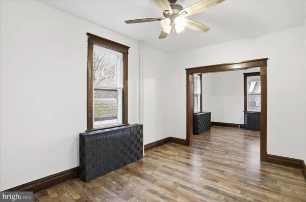 an empty room with wooden floor fan and windows