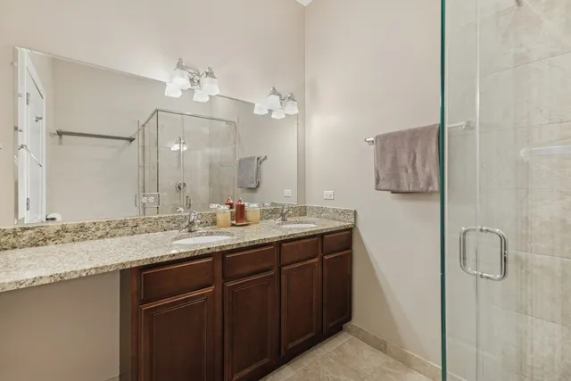 a bathroom with a granite countertop sink a mirror and shower