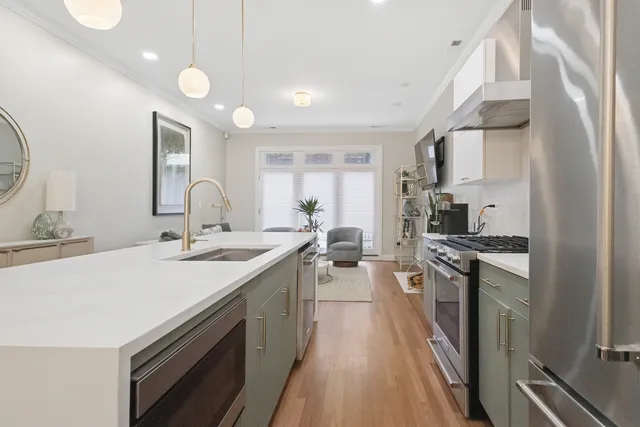 a large kitchen with stainless steel appliances a sink dishwasher a stove and a refrigerator with wooden floor