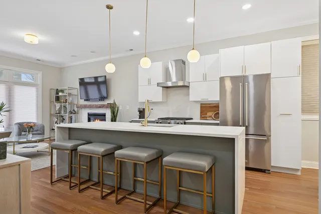 a kitchen with stainless steel appliances granite countertop a sink a stove a refrigerator and chairs