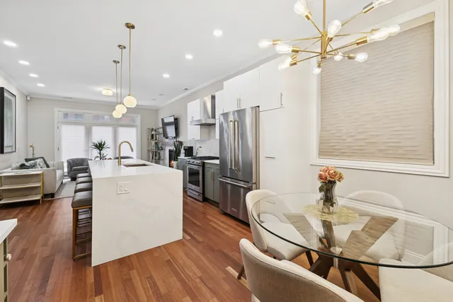 a kitchen with stainless steel appliances kitchen island granite countertop a refrigerator a stove a sink and a dining table with wooden floor