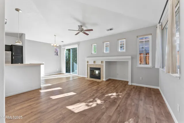 a view of a livingroom with a fireplace a ceiling fan and windows